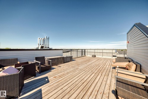 Expansive rooftop deck featuring wood plank flooring and a metal railing - #404 12804 140 Av Nw, Edmonton, AB 