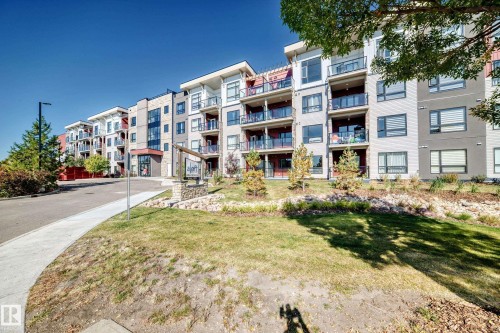 Modern multi-story building exterior with multiple balconies, a paved walkway, and a landscaped entrance - #404 12804 140 Av Nw, Edmonton, AB 