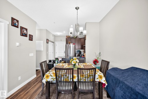 Dining area featuring wood-finish flooring and a contemporary chandelier - #404 12804 140 Av Nw, Edmonton, AB 