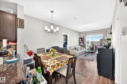 Open-concept living space with wood-finish flooring, a contemporary chandelier, and a bright sliding glass door - 