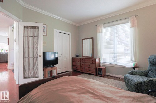 Recessed window with blinds and drapes, crown molding, double-door closet, and wood-finish flooring - 995 Ogilvie Boulevard Nw, Edmonton, AB 