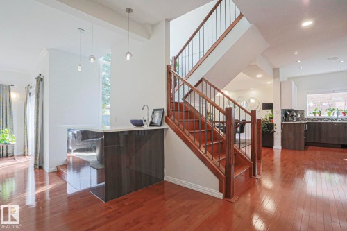 Hardwood flooring throughout, modern staircase with wood handrails and metal balusters, recessed lighting, built-in wet bar with sink, and contemporary pendant lighting - 995 Ogilvie Boulevard Nw, Edmonton, AB 