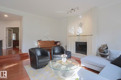 Wood-finish flooring throughout, a built-in fireplace with a stone surround, recessed lighting, and crown molding - 995 Ogilvie Boulevard Nw, Edmonton, AB 