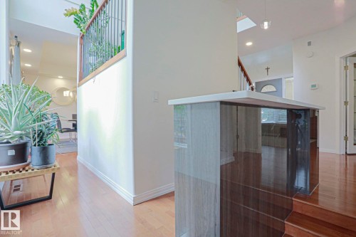 Hardwood flooring throughout, contemporary staircase railing, built-in display niche with reflective panels, recessed lighting, and a skylight - 995 Ogilvie Boulevard Nw, Edmonton, AB 
