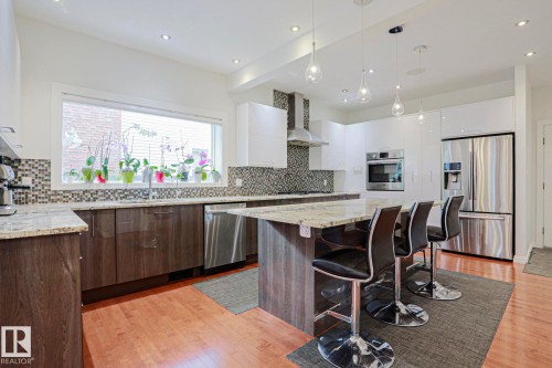 Contemporary kitchen with wood-finish flooring, stainless steel appliances, a large center island, and recessed lighting throughout - 995 Ogilvie Boulevard Nw, Edmonton, AB 