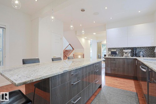 Kitchen featuring an expansive island with a light-toned countertop, wood-finish flooring, recessed lighting, and pendant light fixtures - 995 Ogilvie Boulevard Nw, Edmonton, AB 