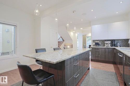 Kitchen featuring a central island with countertop seating, recessed lighting, pendant lighting, wood-finish flooring, and a mosaic tile backsplash - 995 Ogilvie Boulevard Nw, Edmonton, AB 