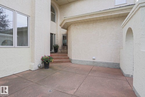 Stucco exterior with an arched entryway and a concrete patio - 995 Ogilvie Boulevard Nw, Edmonton, AB 