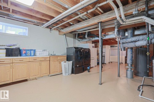 Utility room with wood cabinetry, a utility sink, and ample counter space - 995 Ogilvie Boulevard Nw, Edmonton, AB 