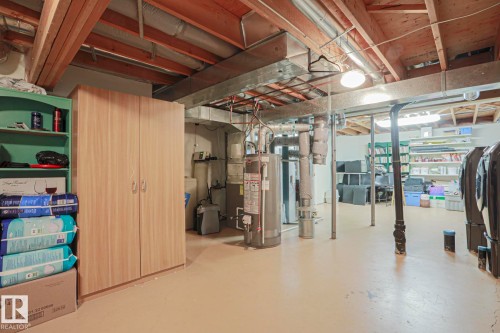 Utility room with exposed ceiling joists and ductwork, featuring a water heater and concrete flooring - 995 Ogilvie Boulevard Nw, Edmonton, AB 