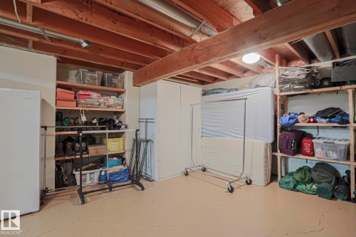 Exposed wood beam ceiling, built-in shelving, painted concrete flooring, recessed wall storage, and ceiling-mounted lighting - 995 Ogilvie Boulevard Nw, Edmonton, AB 