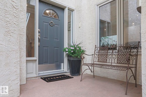 Textured stucco exterior with a paneled entry door featuring an arched transom window and sidelight - 995 Ogilvie Boulevard Nw, Edmonton, AB 