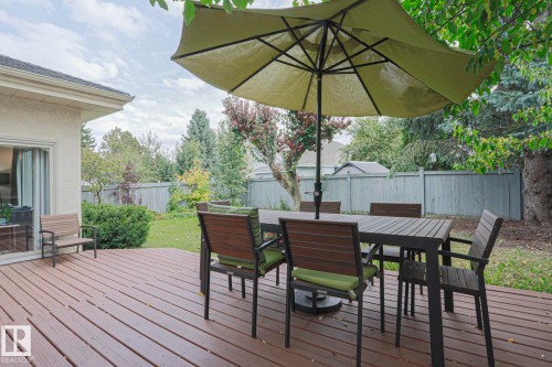 Expansive backyard deck featuring durable composite decking, mature trees, a privacy fence, and a sliding glass door for interior access - 995 Ogilvie Boulevard Nw, Edmonton, AB 