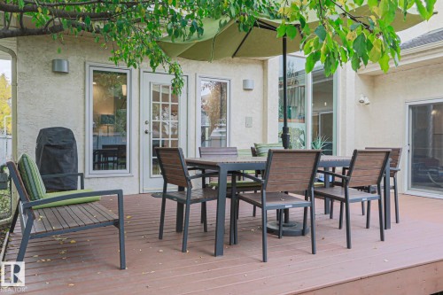 Expansive outdoor deck with a textured stucco exterior, multiple glass doors, and a sliding glass door - 995 Ogilvie Boulevard Nw, Edmonton, AB 
