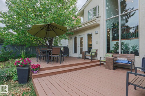 Multi-level wood-finish deck with ample outdoor space, featuring a mature tree, and large windows - 995 Ogilvie Boulevard Nw, Edmonton, AB 