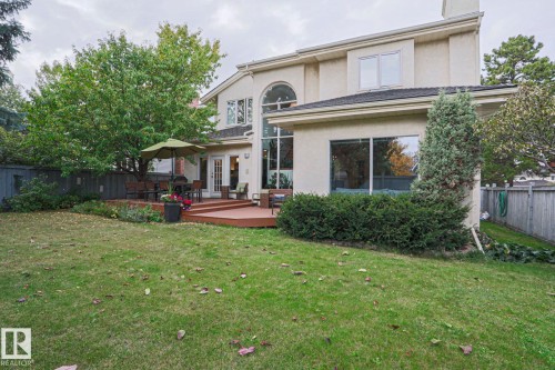 Expansive green lawn, a large wooden deck, two sets of French doors, and a decorative arched window - 995 Ogilvie Boulevard Nw, Edmonton, AB 