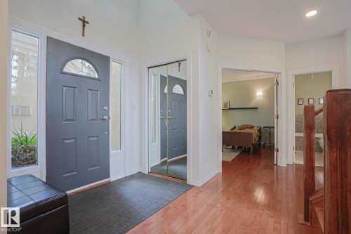Entryway featuring a paneled door with an arched transom, sidelight windows, and a mirrored closet - 995 Ogilvie Boulevard Nw, Edmonton, AB 