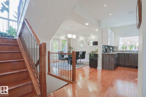 Hardwood flooring throughout, a staircase with wood railing and iron balusters, recessed lighting, and a kitchen with two-tone cabinetry and mosaic tile backsplash - 995 Ogilvie Boulevard Nw, Edmonton, AB 