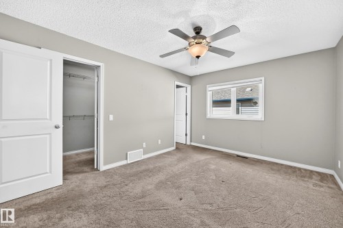 Neutral color palette with textured carpeting, ceiling fan with integrated lighting, and white trim throughout - 21 Silverstone Drive, Stony Plain, AB 