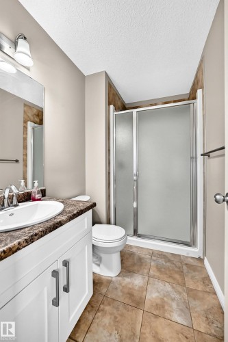 White vanity with dark hardware, a surface-mounted sink, and a dark stone-finish countertop - 21 Silverstone Drive, Stony Plain, AB 