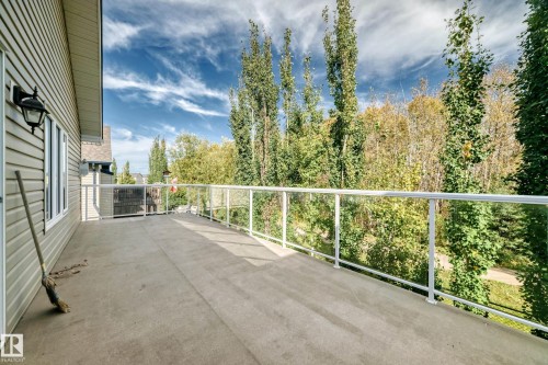 Expansive concrete deck featuring clear panel railings and exterior wall lighting - 21 Silverstone Drive, Stony Plain, AB 