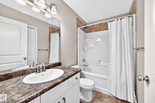 White vanity with cabinet storage, a wide oval sink, and a speckled countertop - 21 Silverstone Drive, Stony Plain, AB 