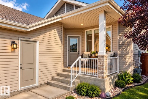 Covered porch with stone column accents, concrete steps, and a decorative railing - 21 Silverstone Drive, Stony Plain, AB 
