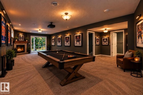 Spacious entertainment room with neutral carpeting, a corner fireplace featuring a wood mantel, and glass sliding doors - 21 Silverstone Drive, Stony Plain, AB 