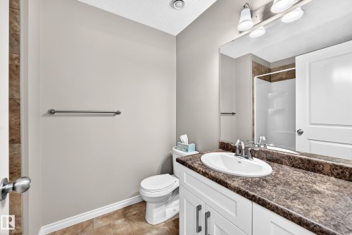 Bathroom featuring a white vanity with dual-handle faucet, integrated sink, and a speckled countertop - 21 Silverstone Drive, Stony Plain, AB 
