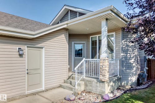 Covered front entrance with stone accent pillar, featuring a privacy glass entry door and transom window - 21 Silverstone Drive, Stony Plain, AB 