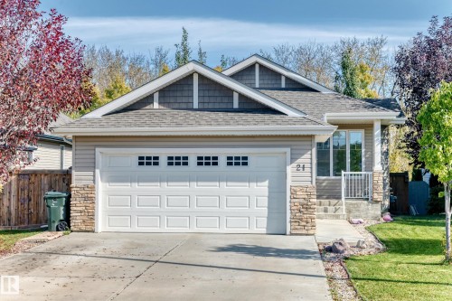 Exterior featuring a covered entry, stone accents, shingle siding, and a paneled garage door with window inserts - 21 Silverstone Drive, Stony Plain, AB 