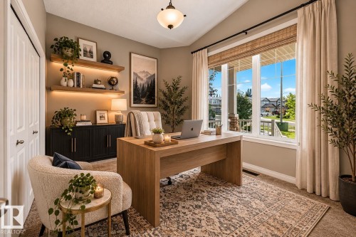 Vaulted ceiling with an overhead light fixture, large window with blinds and drapes, built-in shelving with integrated lighting, and a built-in storage cabinet - 21 Silverstone Drive, Stony Plain, AB 