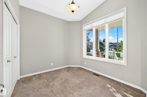 Recessed window with white trim, wall-to-wall carpeting, and a built-in closet with bifold doors - 21 Silverstone Drive, Stony Plain, AB 