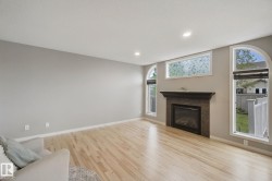 Bright, open living space featuring gleaming wood-finish flooring, recessed lighting, and abundant natural light from multiple windows - 