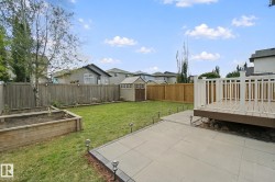 Expansive backyard featuring a raised wooden planter, lawn, storage shed, and a composite deck with white railings - 