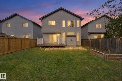 Expansive backyard featuring a manicured lawn, a raised wood deck with white railings, and a wood privacy fence - 