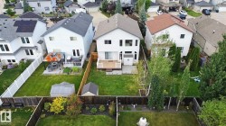 Rear exterior with a wood deck, manicured lawn, and privacy fencing - 
