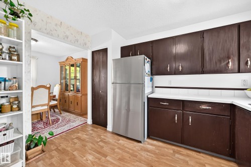 Kitchen featuring wood-finish flooring, dark wood-finish cabinetry, and white countertops - 11007 173A Avenue Nw, Edmonton, AB 
