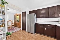 Kitchen featuring wood-finish flooring, dark wood-finish cabinetry, and white countertops - 