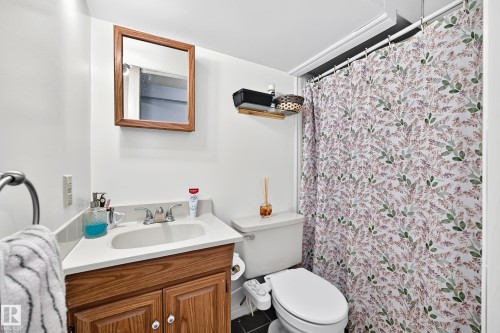 Corner vanity with wood-finish cabinetry, integrated sink, and chrome faucet - 11007 173A Avenue Nw, Edmonton, AB 