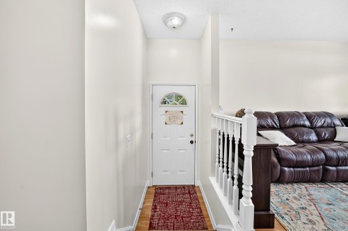 Recessed entry with wood-finish flooring, white paneled door with an arched glass insert, and a ceiling-mounted light fixture - 11007 173A Avenue Nw, Edmonton, AB 