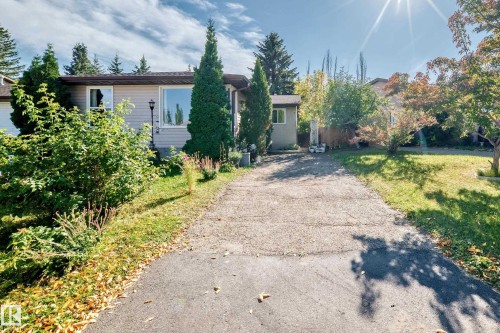 Siding exterior with a paved driveway, featuring mature trees and established landscaping - 11007 173A Avenue Nw, Edmonton, AB 