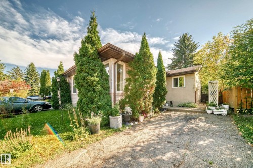 Single-story exterior with stucco and siding elements, featuring a bay window, a paved driveway, and mature landscaping - 11007 173A Avenue Nw, Edmonton, AB 