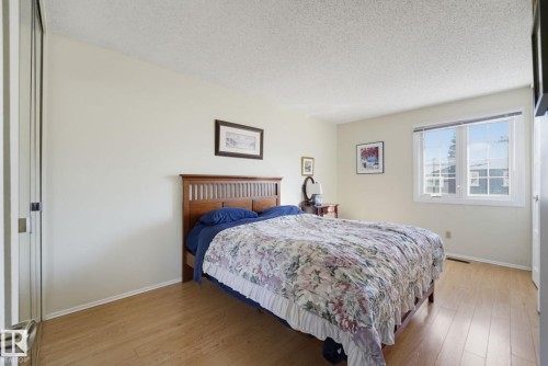 Bright room featuring wood-finish flooring, a large window, and light-toned walls - 17072 67 Avenue Nw, Edmonton, AB 