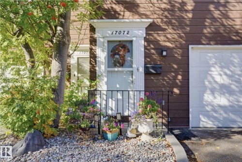 Brown horizontal siding, white trim around the entry, black metal handrail, and white garage door - 17072 67 Avenue Nw, Edmonton, AB 