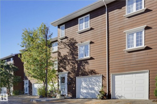 Brown horizontal siding with white trim windows and white garage doors - 17072 67 Avenue Nw, Edmonton, AB 