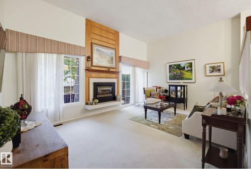 Living area featuring a vaulted ceiling, wood-paneled fireplace surround, integrated fireplace, white mantel, and glass-paneled exterior doors - 17072 67 Avenue Nw, Edmonton, AB 