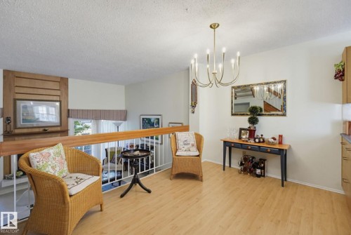 Wood-finish flooring throughout, with a brass chandelier and white perimeter walls - 17072 67 Avenue Nw, Edmonton, AB 
