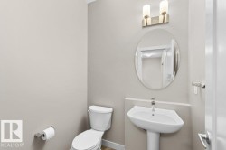 Pedestal sink with a polished chrome faucet, oval mirror, and a two-bulb vanity light fixture - 