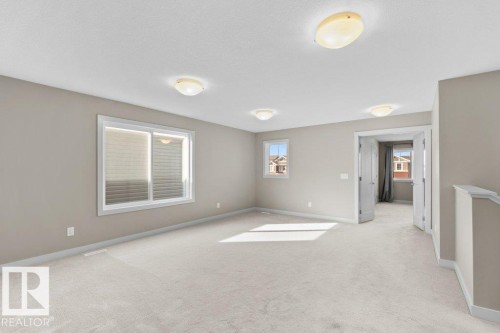 Expansive carpeted room with multiple windows, neutral wall tones, and flush-mount ceiling lighting - 1523 168 Street Sw, Edmonton, AB 